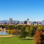 City skyline of Denver Colorado downtown with snowy Rocky Mountains and the City Park Lake